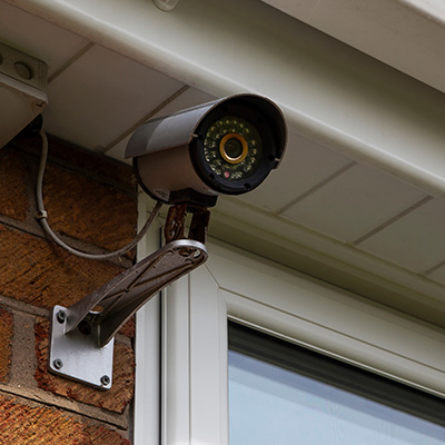 CCTV camera mounted on a brick wall near a window in Manchester.