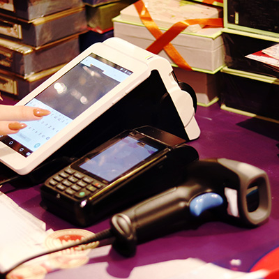 EPOS system with tablet, mobile, and barcode scanner on a retail counter.