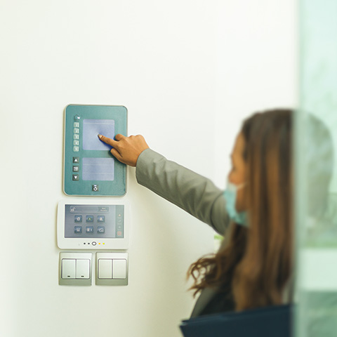 Woman interacting with security system control panel on a wall