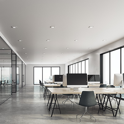 Modern office space with desks, computers, and large windows.