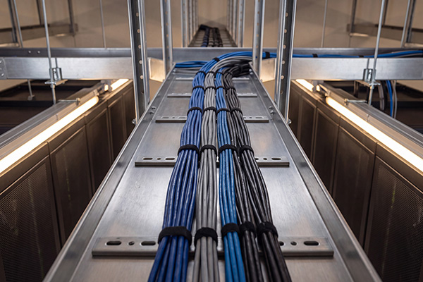 Structured cabling installation with copper and fibre cables in a commercial setting.