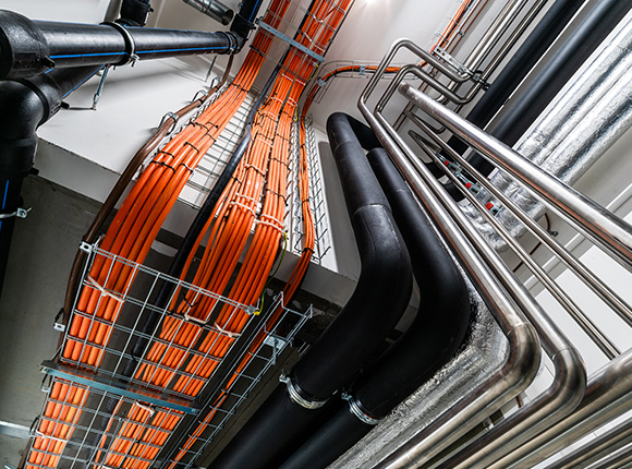 Network cabling with orange and black pipes in a structured installation setup.