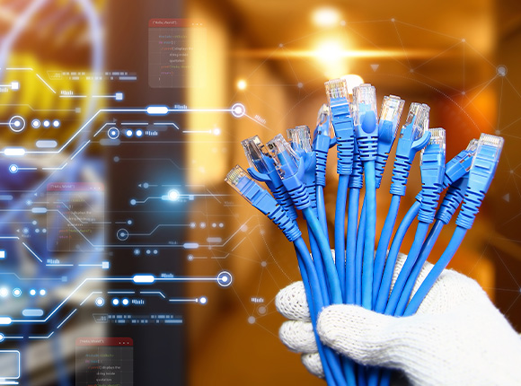 Blue network cables held in a gloved hand with a blurred background.