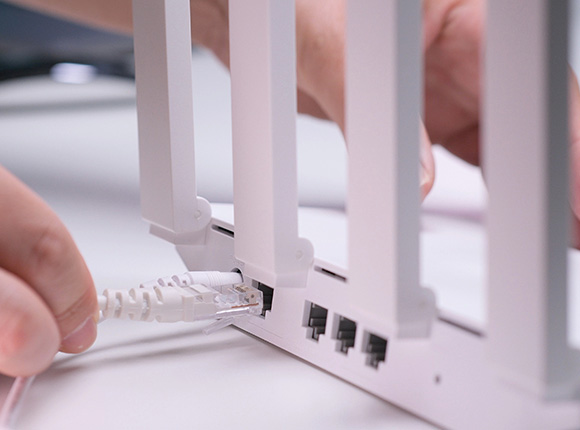 Connecting an Ethernet cable to a network device with antennas.