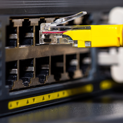 Close-up of a fiber optic cable connection being plugged into a network switch.