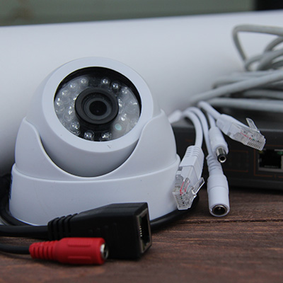 CCTV camera with cables and connectors on a wooden surface.
