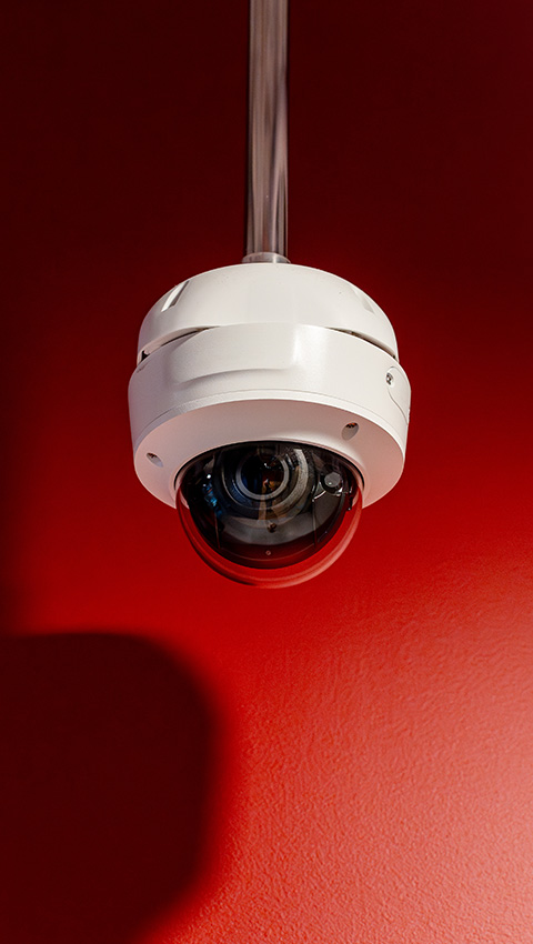 CCTV camera mounted on a red wall, showcasing security surveillance technology.