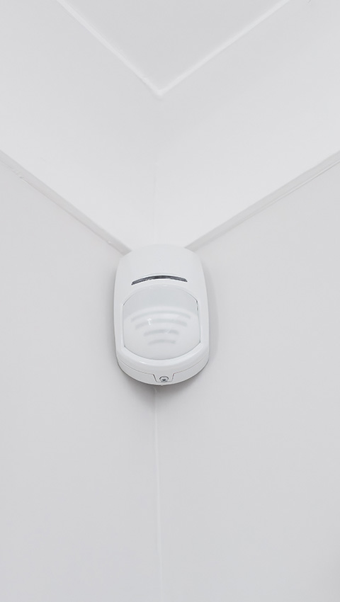Residential alarm system installed in a corner of a white room.