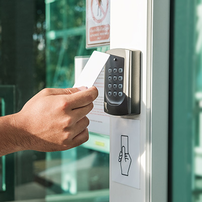 Hand using a card to access a security system at a door.