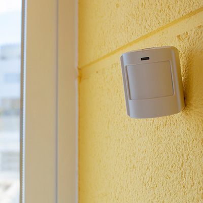 CCTV camera mounted on a yellow wall, providing security surveillance.