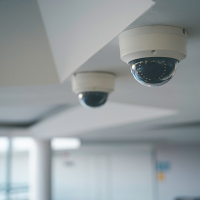 Two security cameras mounted on a ceiling in a modern interior space.
