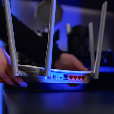Residential Wi-Fi router being installed with visible Ethernet ports and antennas.