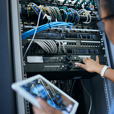 Technician managing structured cabling and IT equipment in a server rack.