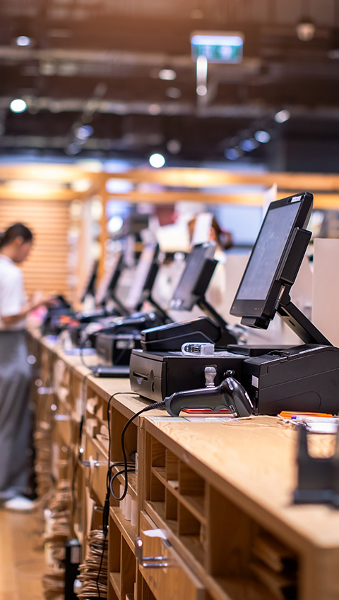 Modern point-of-sale systems arranged neatly on a wooden counter in a retail environment.
